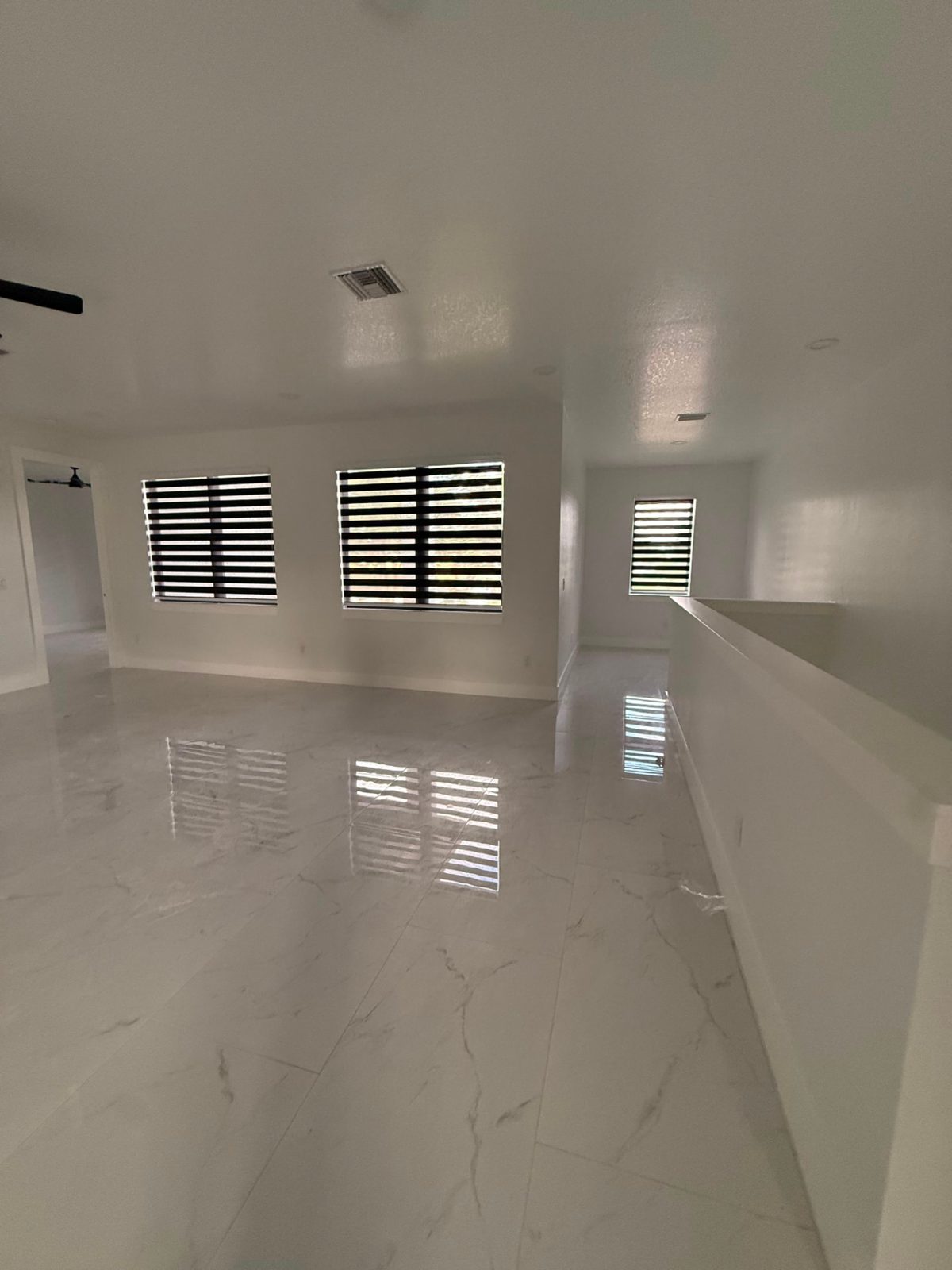 Three matching zebra shades on an open loft with polished marble tile reflecting the light bands